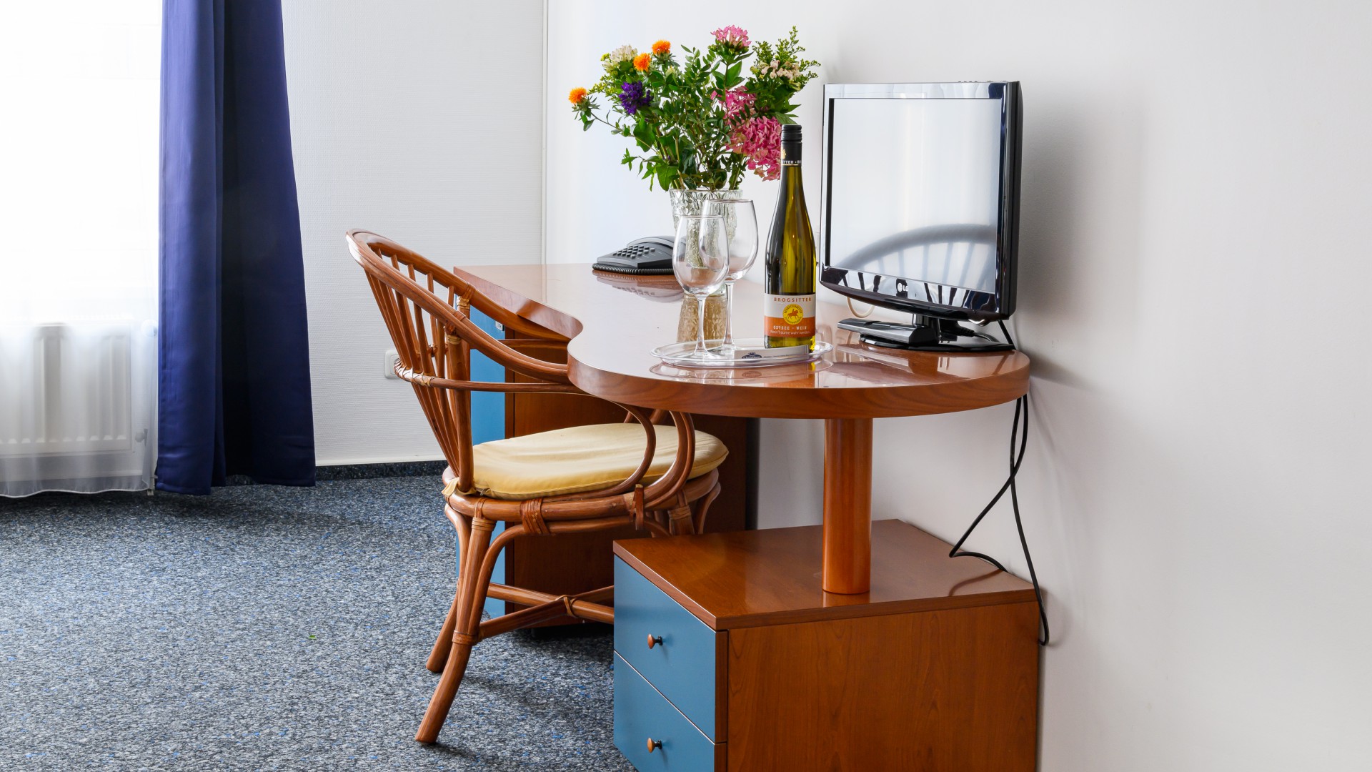 Schreibtisch mit Blumen und TV im Hotelzimmer